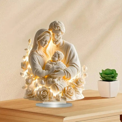 Decorative statue of a family with lights on a wooden surface with a plant in the background