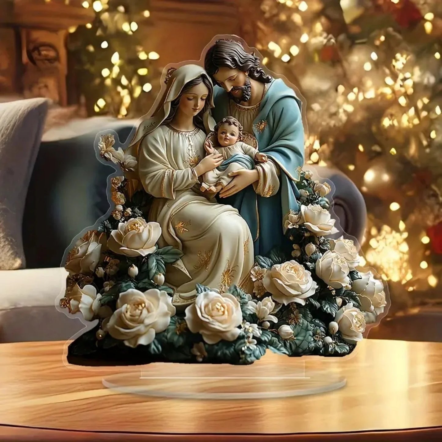 Decorative figurine of the Holy Family with flowers on a wooden surface, Christmas tree in the background.